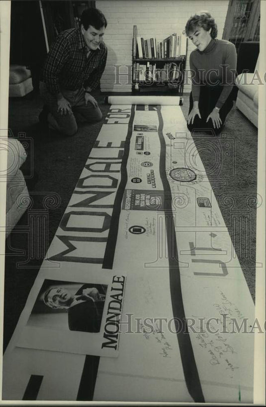 1984 Press Photo Michael & Ellen Bartell examine Walter Mondale banner - Historic Images