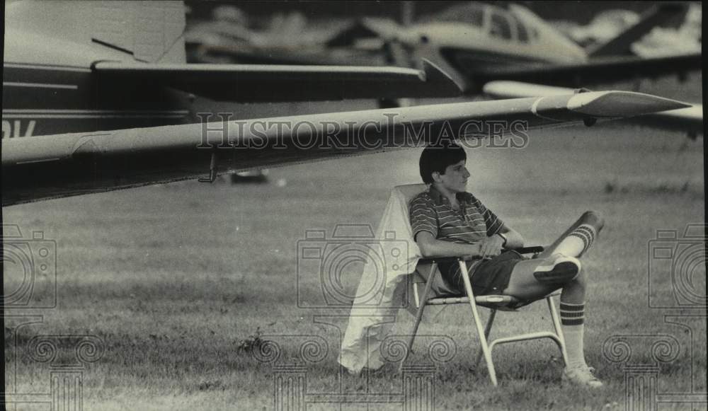 1985 Press Photo Dan Ruleman sitting under wing of his Beechcraft, Oshkosh - Historic Images