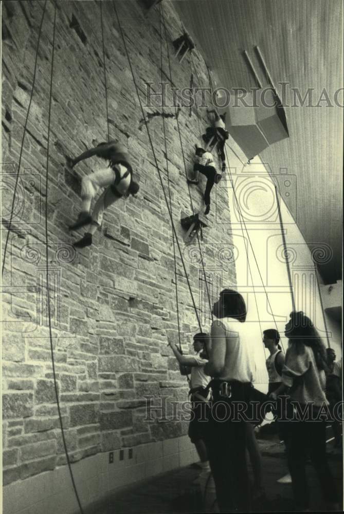 1988 Press Photo Climbers crawl up wall at University of Wisconsin - River Falls - Historic Images