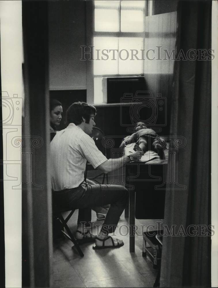 1970, Migrant mother gives information about child to Dr. Abramson. - Historic Images