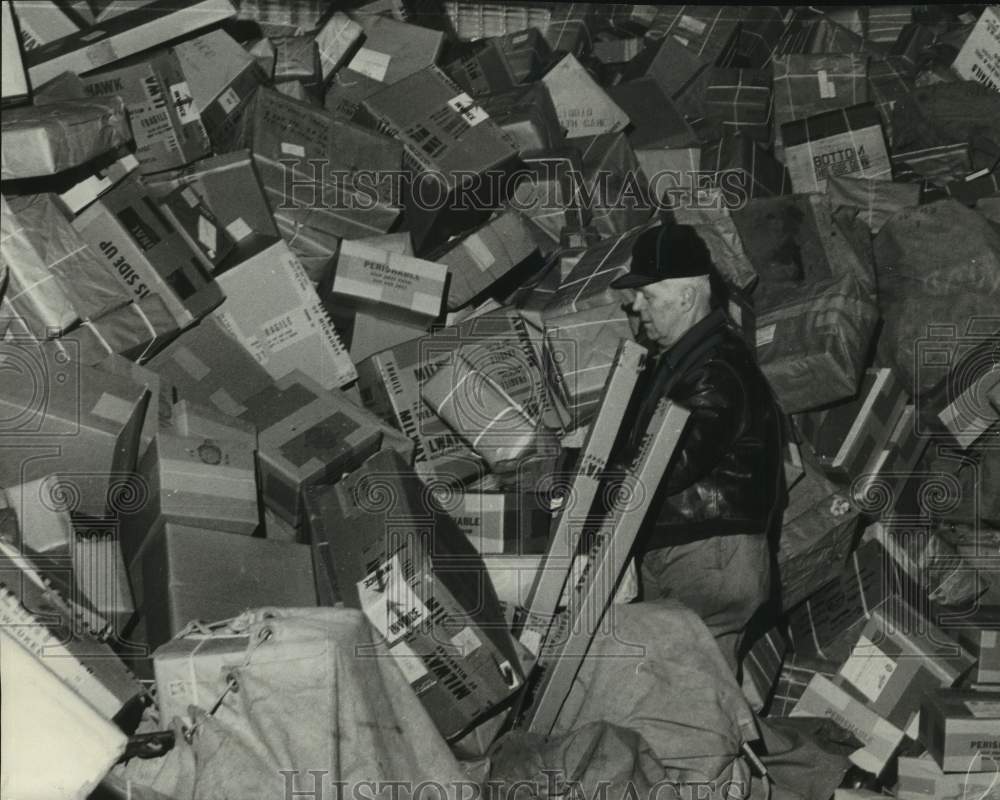 1956 Press Photo Postal worker sorts through mountain of packages in Milwaukee - Historic Images