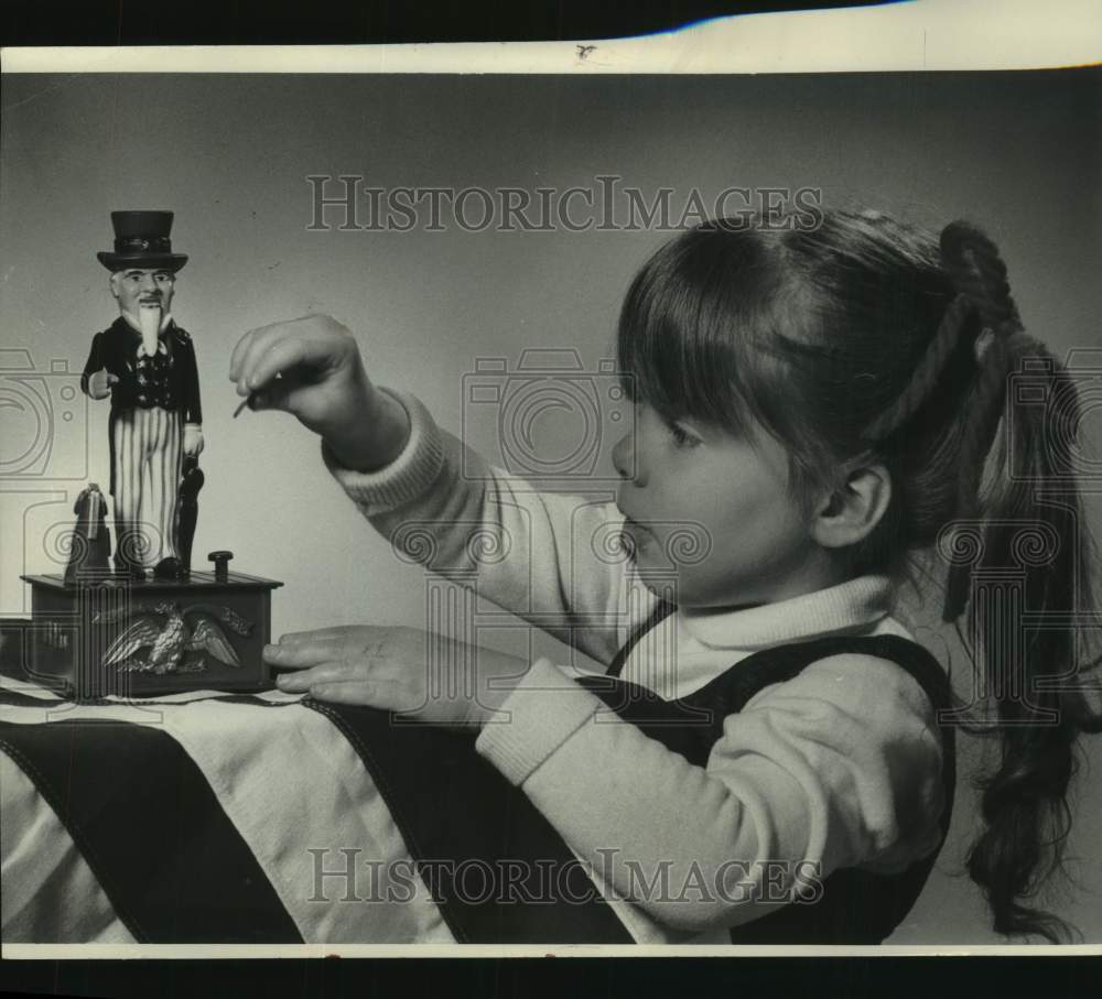 1976 Press Photo Young girl putting coins in Uncle Sam bank, Wisconsin - Historic Images