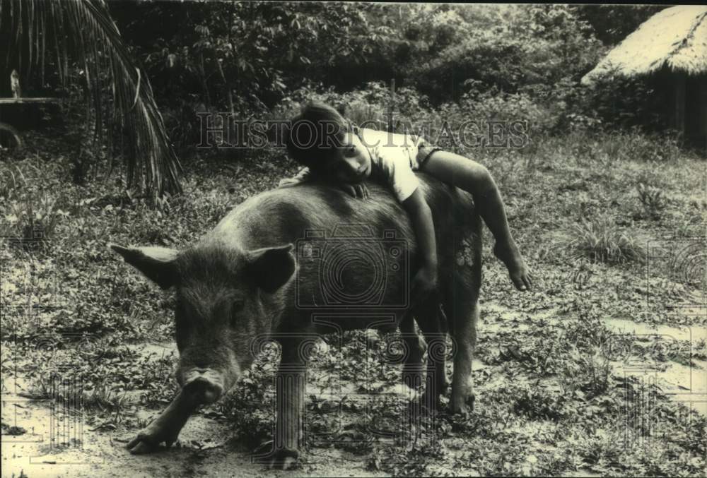 1988 Press Photo Boy playing with a pig, Lake Sandoval, Puerto Maldonado, Peru - Historic Images