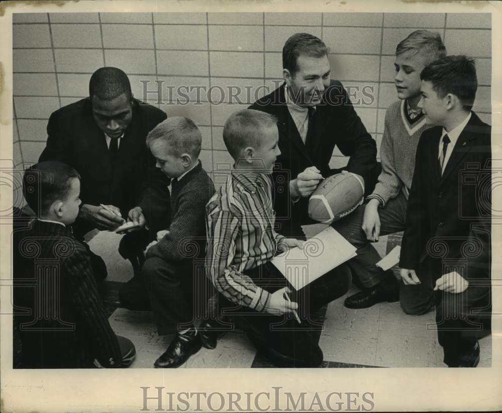 1963, Athletes Lee Maye and Bart Starr sign autographs for boys. - Historic Images