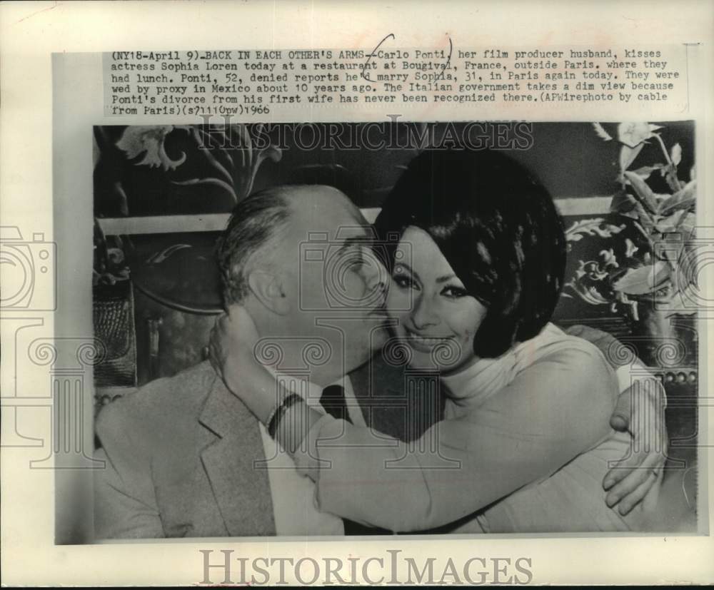 1966 Press Photo Carlo Ponti kisses his wife Sophia Loren in Bougival, France. - Historic Images