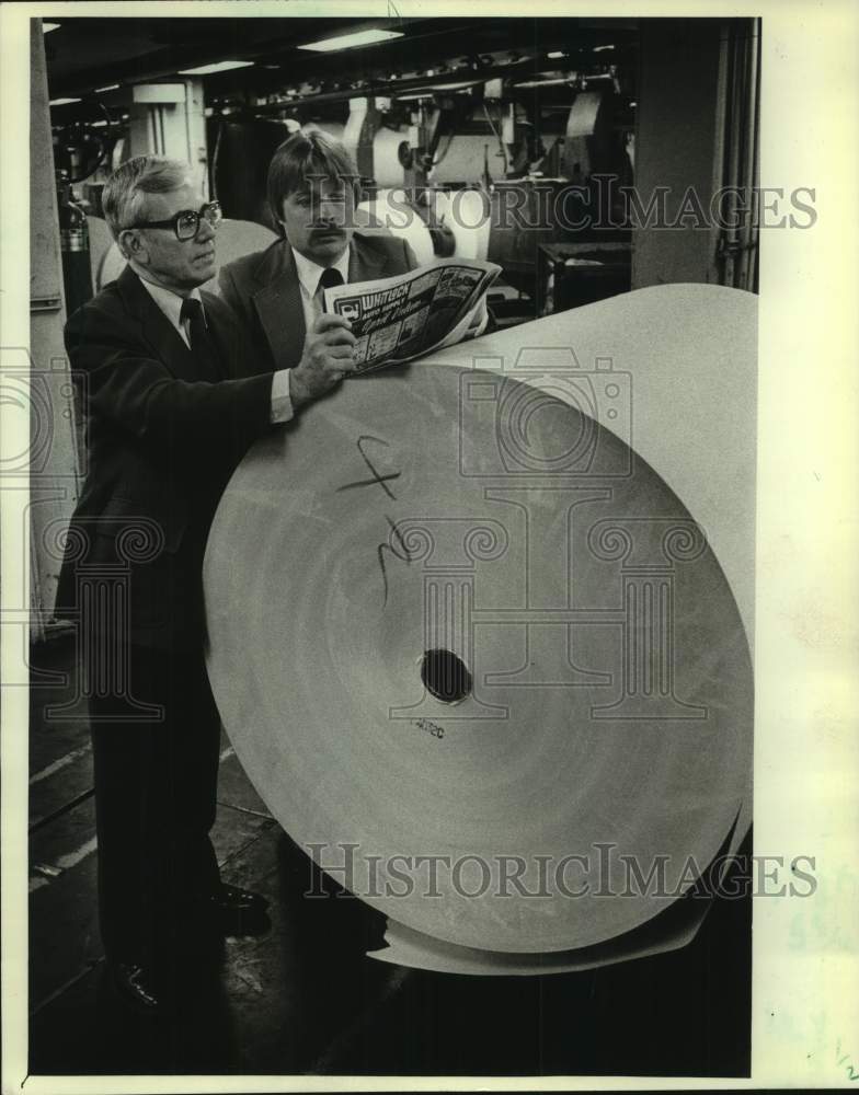 1982, examined Men check new paper roll for Centennial Purchasing - Historic Images