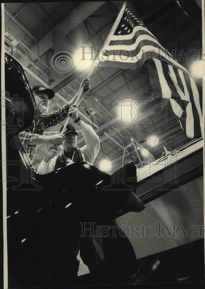1992 Press Photo James Becker hangs flag at Milwaukee Sentinel's Sports Show, WI - Historic Images