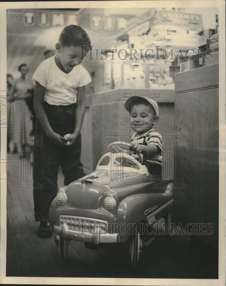 1954, Children of Menominee Indians play with a toy car in a store - Historic Images