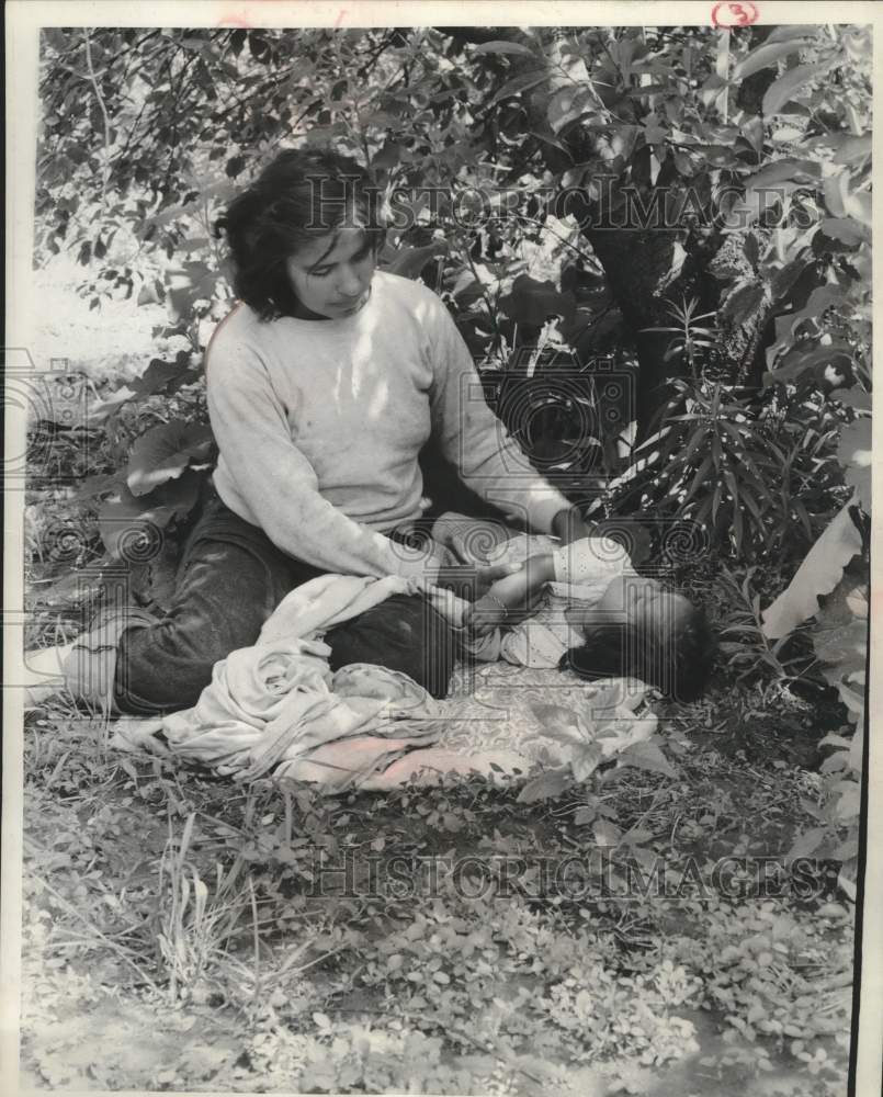 1956, Mathenoluah watches her sleeping daughter Enemqua under a tree - Historic Images
