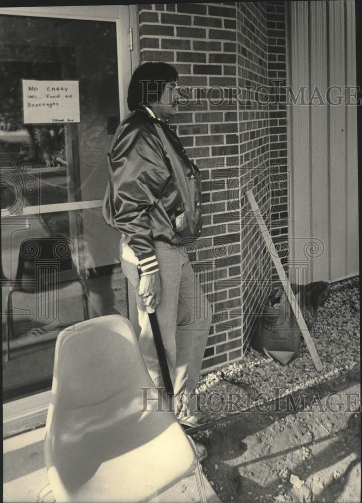 1984 Press Photo Winnebago Indian man stands in front of store with stick, WI - Historic Images