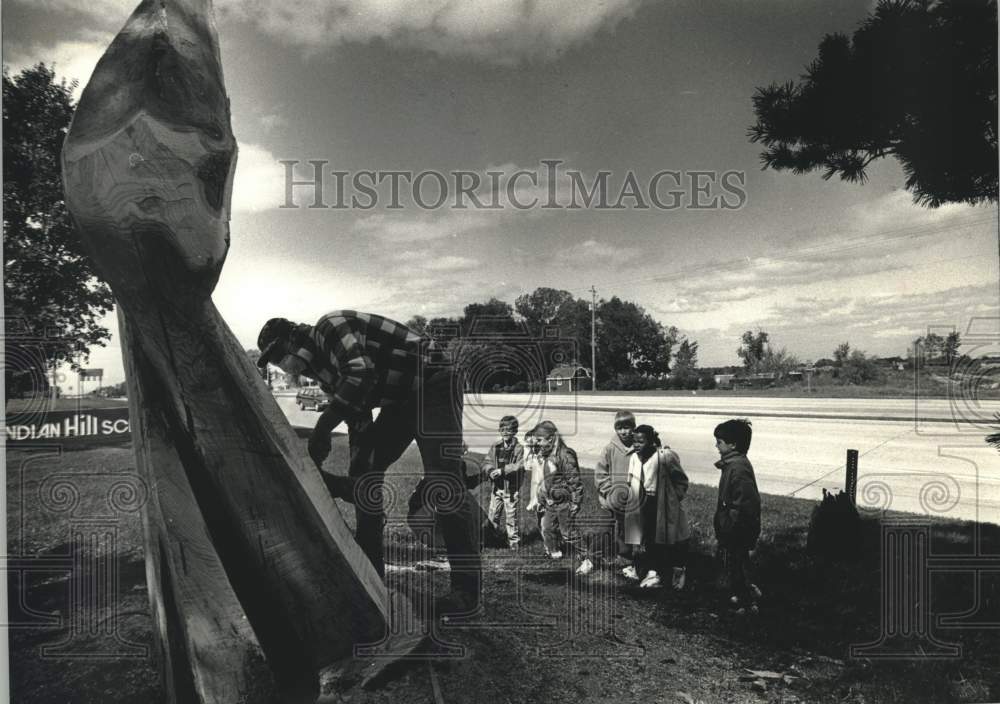 1991 Press Photo Artist Tom Queoff finishes wood sculpture for school. - Historic Images