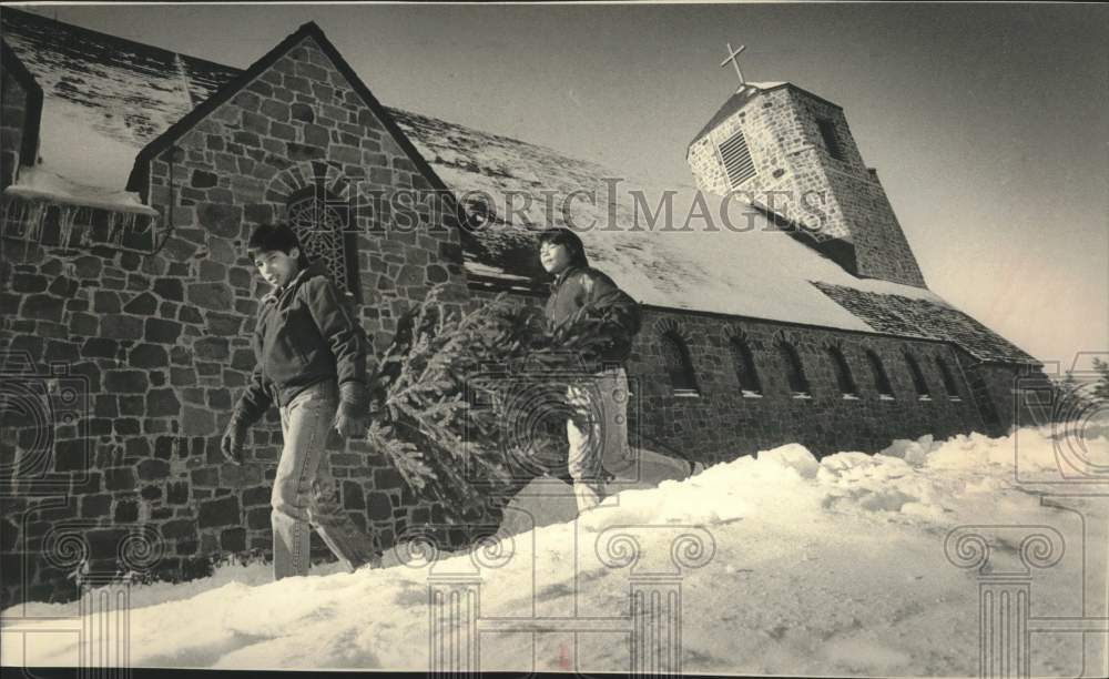 1988 Press Photo Chippewa youth carry Christmas tree to church convent - Historic Images
