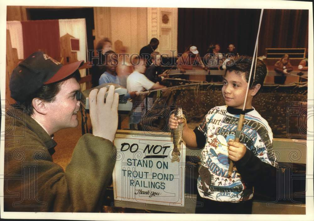 1994 Press Photo Brian Bender takes a picture of a trout held by Edgardo Vargas - Historic Images