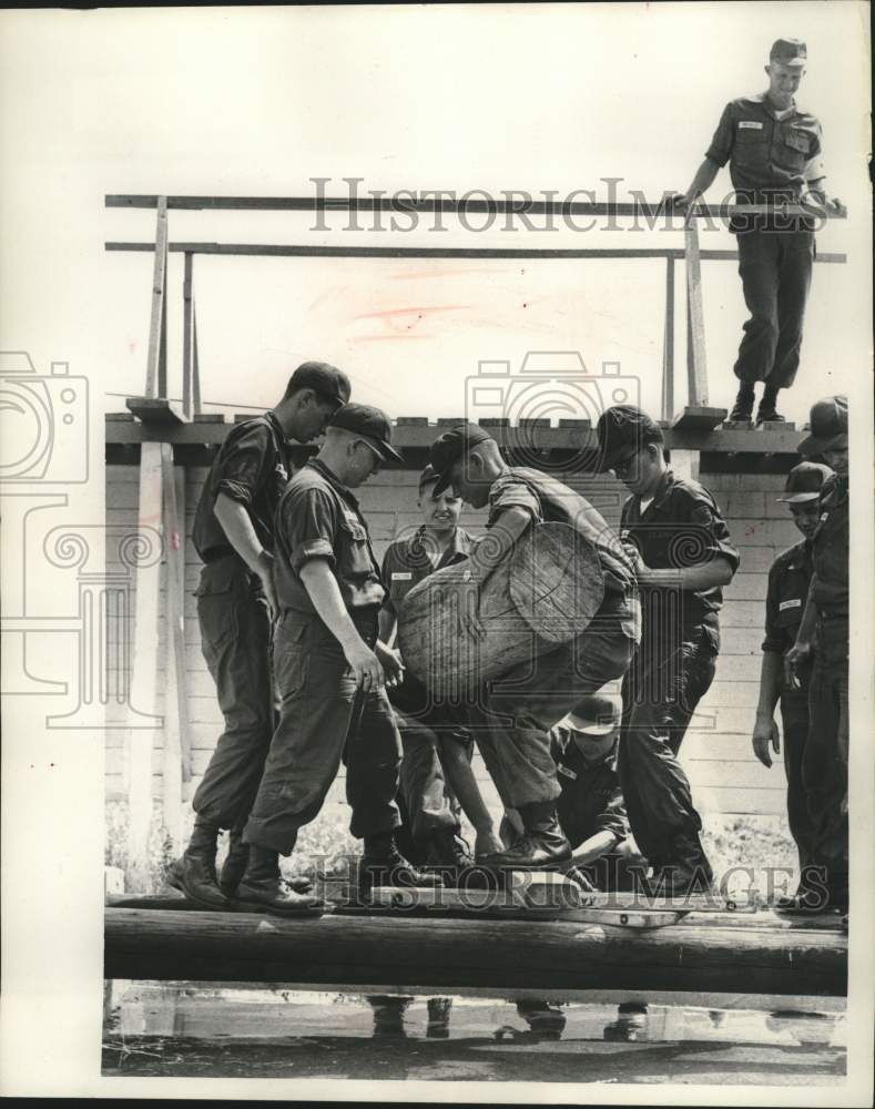 1966, US Army Teammates help Donald Stuempfig carry log across water - Historic Images