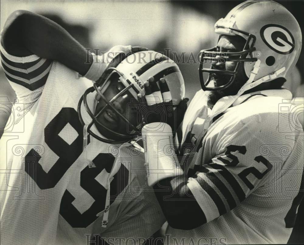 1980 Press Photo Green Bay Packers' football player helps teammate with helmet - Historic Images