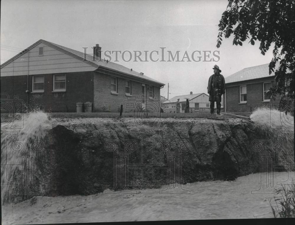 1957 Milwaukee fireman watches pumpers drain floodwater into ditch - Historic Images