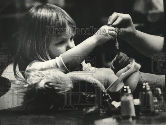 1974 Press Photo girl gives doll shot, Milwaukee Children's Hospital of WI - Historic Images