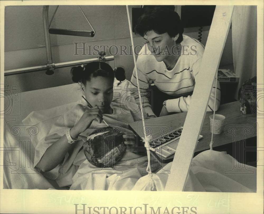 1984 Press Photo Child Life intern Pam Oxman helps Belinda Fields make a pinata - Historic Images