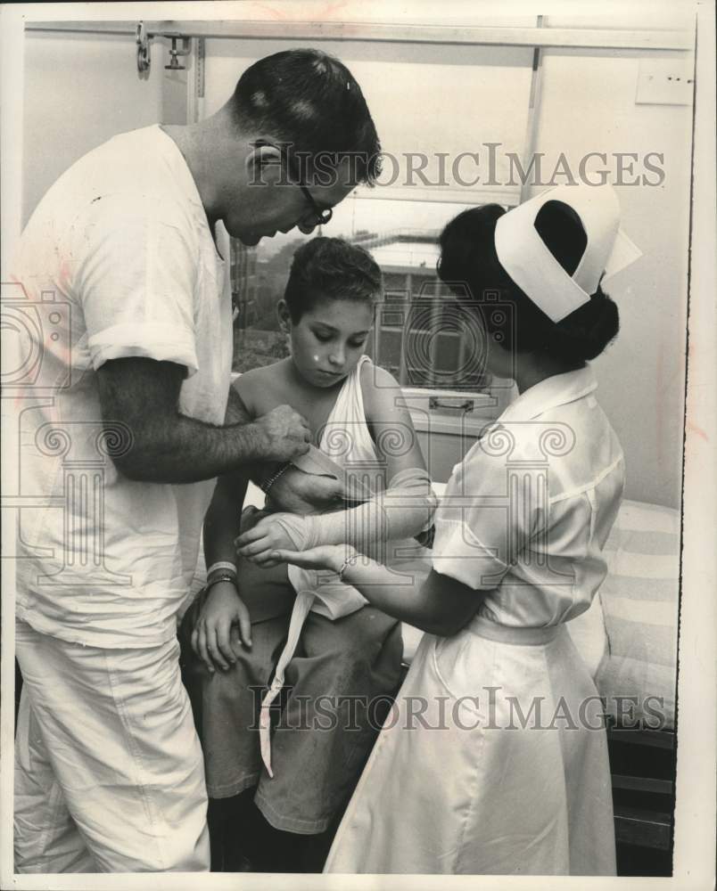 1957, Dr. Gerald Gredler adjusts sling for patient George Pasdirtz - Historic Images