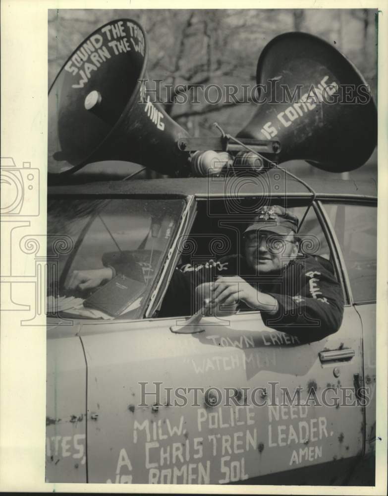 1985 Press Photo Ronald Stanis sitting in car with misspelled words, Milwaukee - Historic Images