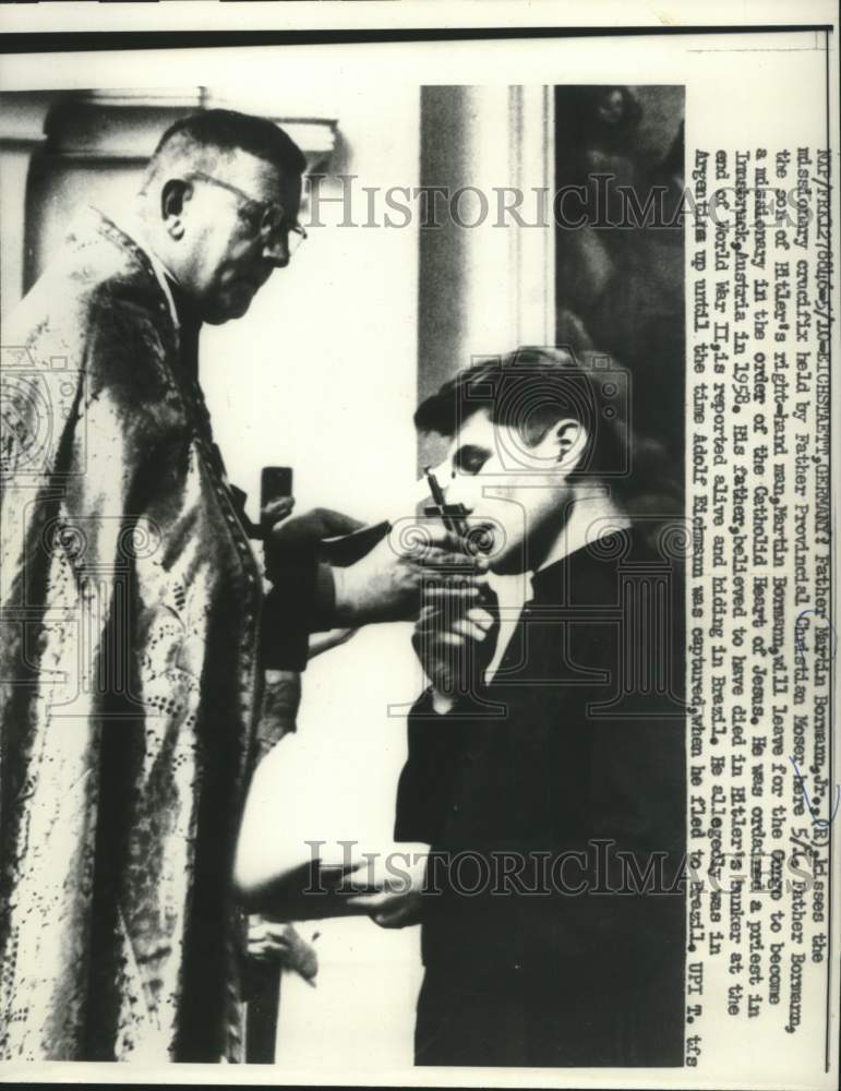 1961, Father Martin Bormann kisses the crucifix of Father Moser - Historic Images