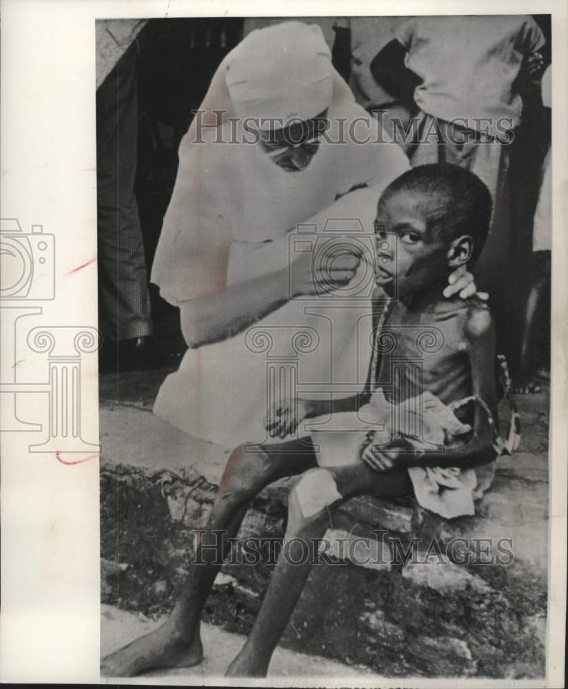 1960 Belgian nurse feeds a child at a refugee camp in the Congo. - Historic Images