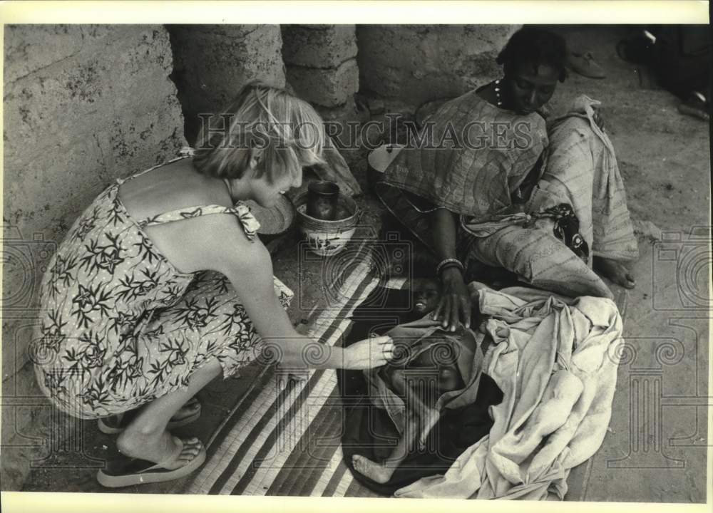 1984 Press Photo Nurse Denise Gowen (L) checks starving child in Burkina Faso. - Historic Images