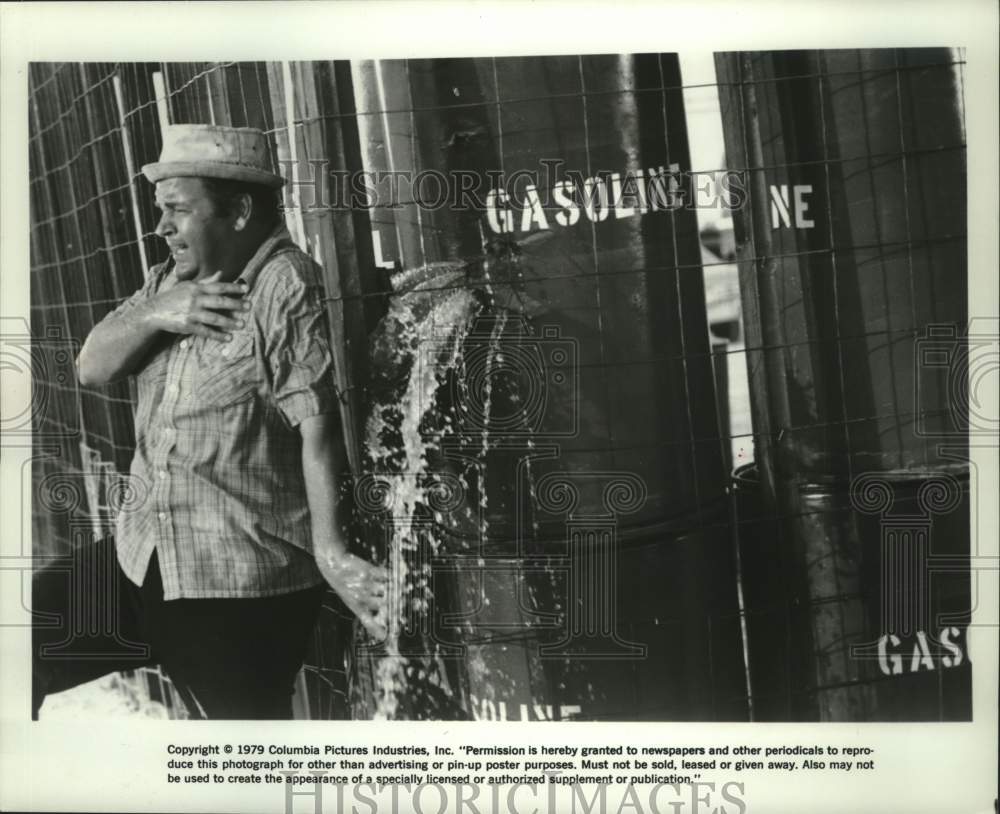 1979 Press Photo Dom DeLuise hides by barrels of gasoline in movie &quot;Hot Stuff.&quot; - Historic Images