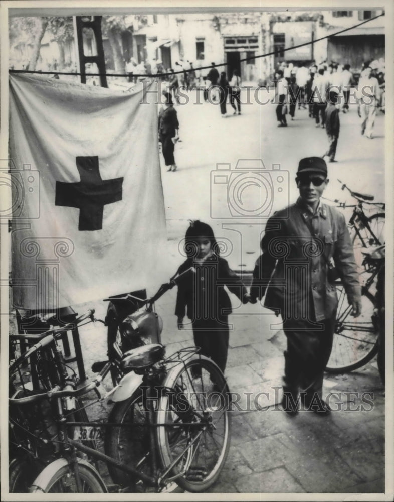 1969 Press Photo Father and daughter walk past Red Cross flag in Hanoi - Historic Images