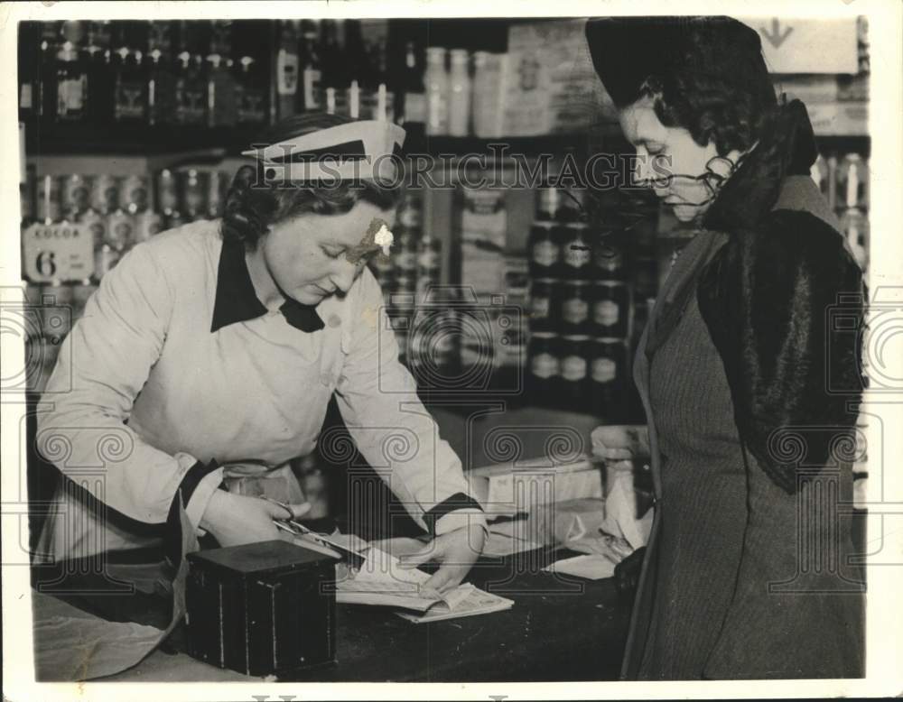 1941 Press Photo Shop Clerk Helps Customer With Ration Book England - mjm08261 - Historic Images