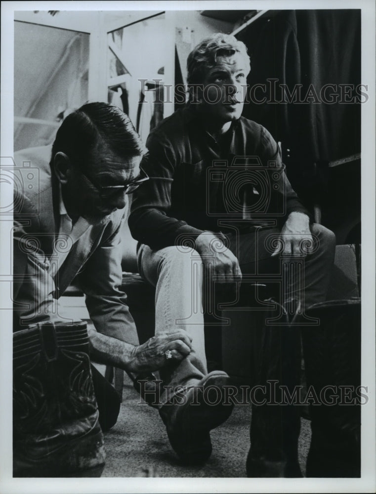 1967 Press Photo Actor Sean Garrison gets help with boot from unidentified man - Historic Images