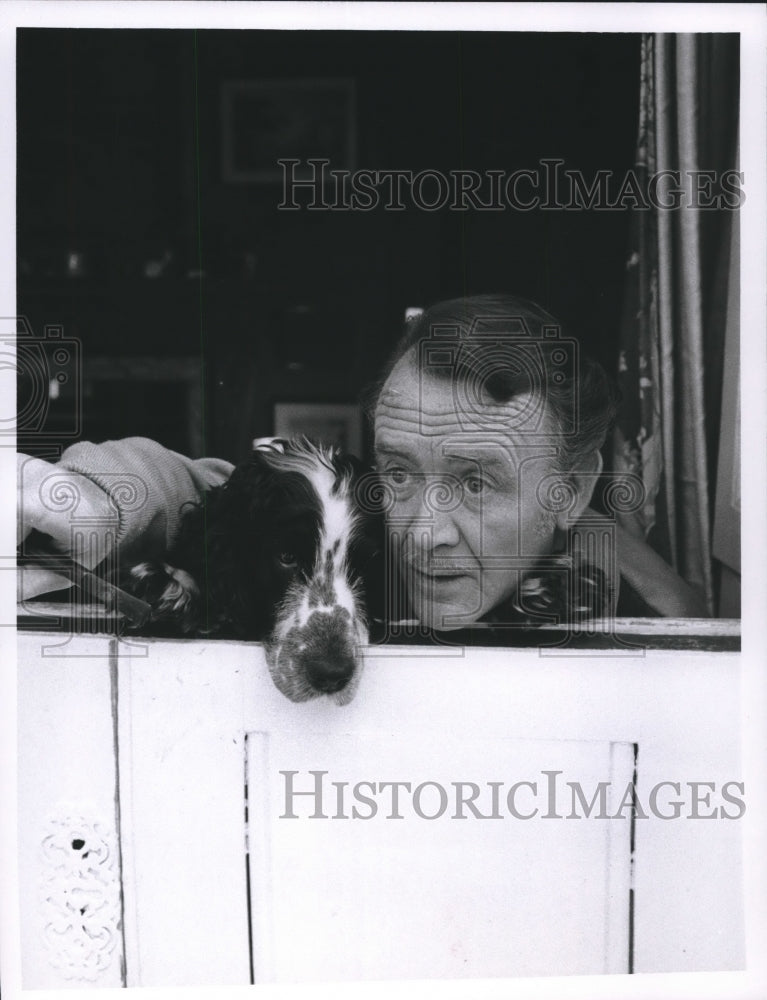 1967, John Mills, and his dog looks out a window - Historic Images