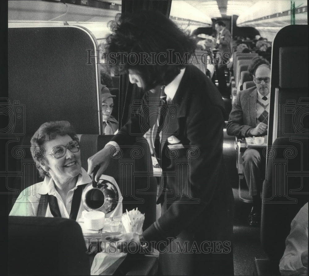 1985 Press Photo Flight Attendant Serves Milwaukee Orchestra&#39;s Audrey Baird - Historic Images