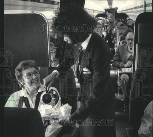 1985 Press Photo Flight Attendant Serves Milwaukee Orchestra's Audrey Baird - Historic Images