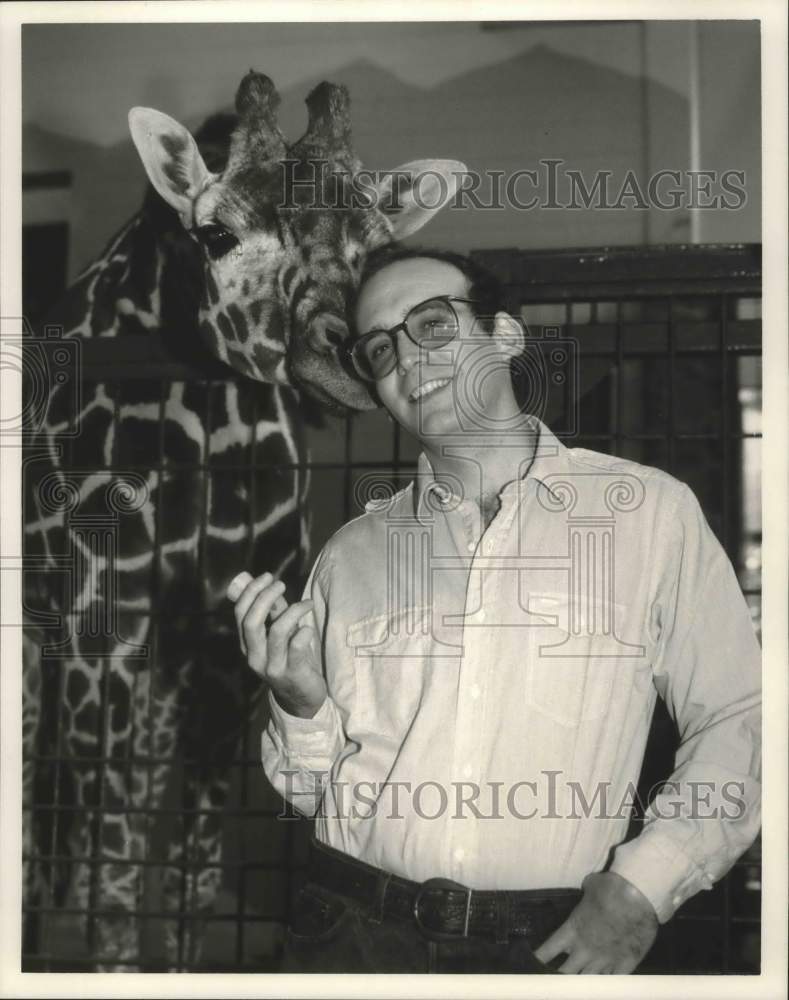 1985, Filmmaker David Lee Miller poses with a giraffe - mjp23165 - Historic Images