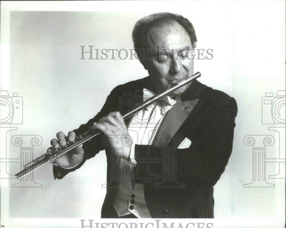 1986, French Flutist Jean-Peirre Rampal playing flute in tuxedo - Historic Images
