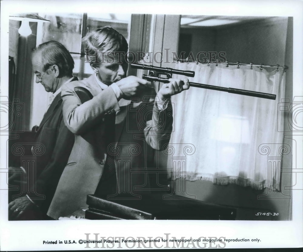 1974, Edward Fox as "The Jackal" examines an assassination weapon - Historic Images
