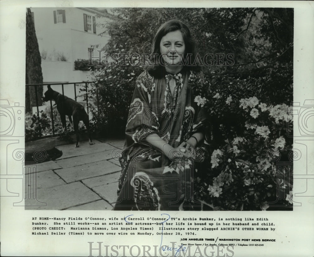 1974, Nancy Fields O&#39;Connor, sits next to flowing bush outside home - Historic Images
