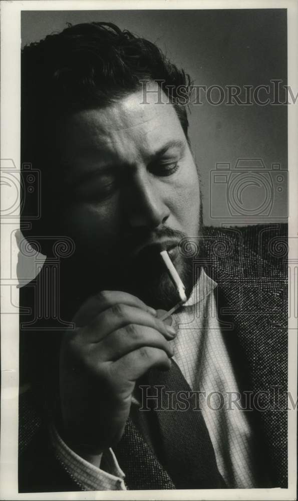 1958, Actor Peter Ustinov lighting a cigarette. - mjp43455 - Historic Images