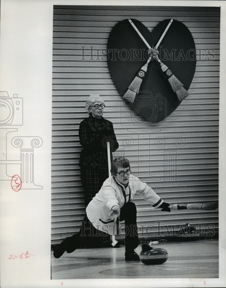 1975 Mrs. Allen Held watches Mrs. S. Bruce deliver a curling stone - Historic Images