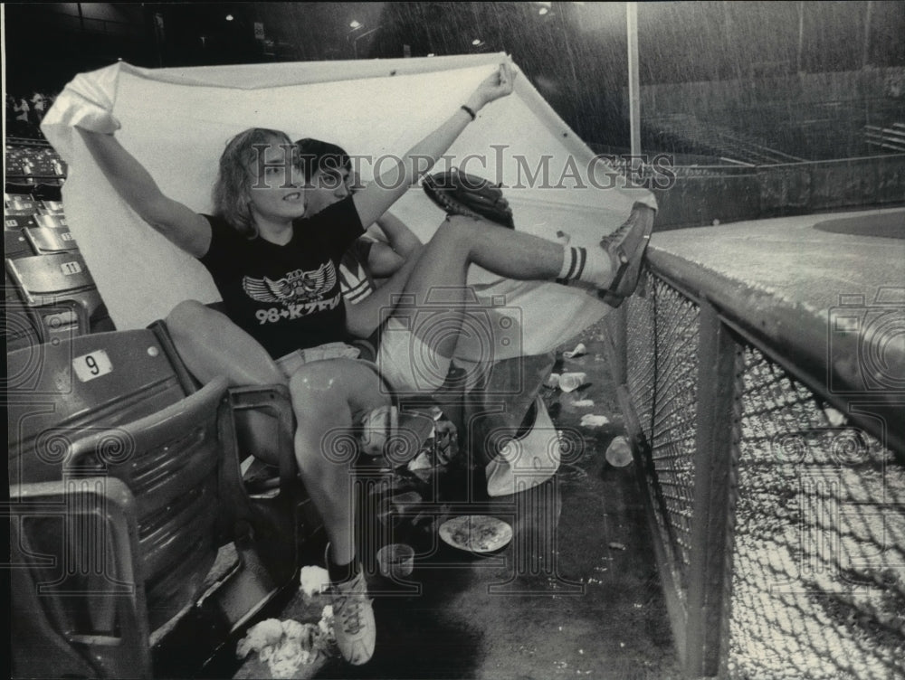 1983 Press Photo Betty Press and brother Mike covered with tarp at Brewers game.- Historic Images