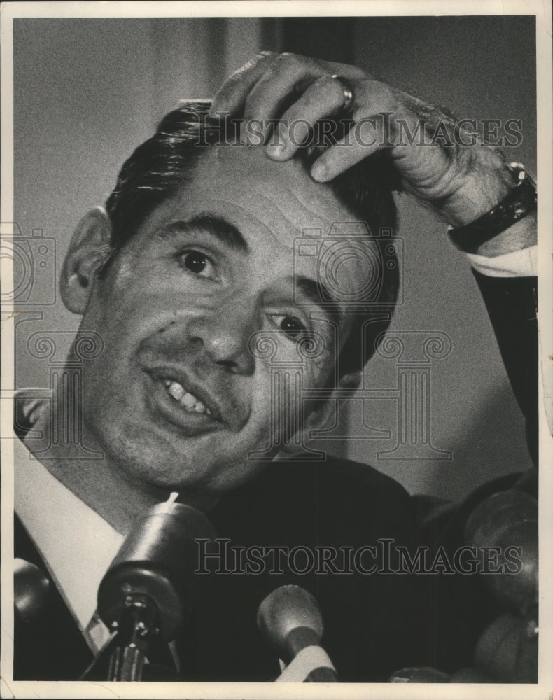 1971 Dan Devine, football coach, holding head and talking to press. - Historic Images