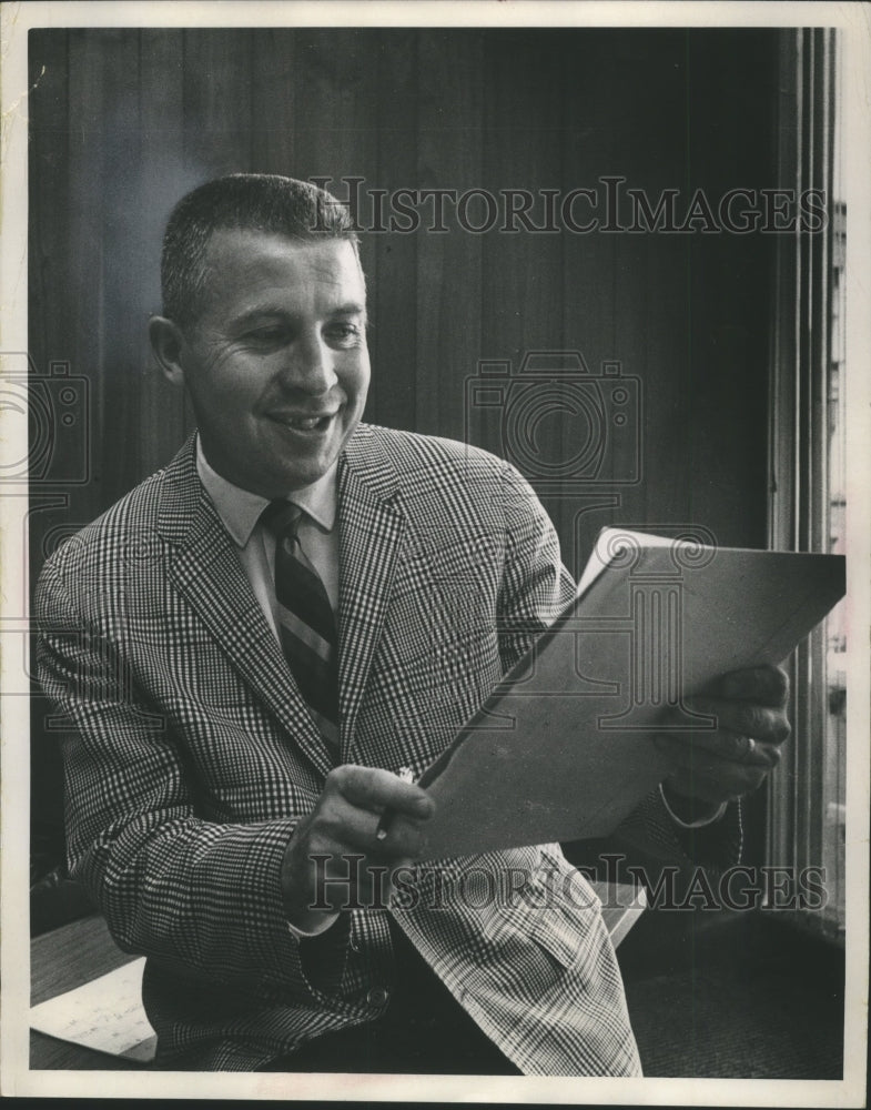 1968 John Erickson, general manager studies player rosters for draft - Historic Images