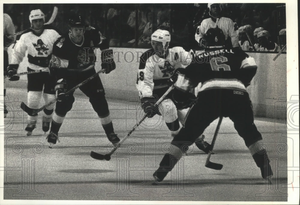 1990 Press Photo Milwaukee hockey&#39;s Peter DeBoer brings puck between 2 defenders - Historic Images