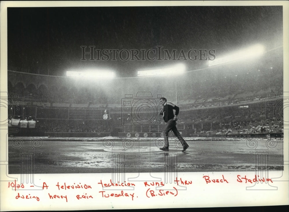 1982 Press Photo Television Technician Runs Across Rainy Field at Busch Stadium - Historic Images