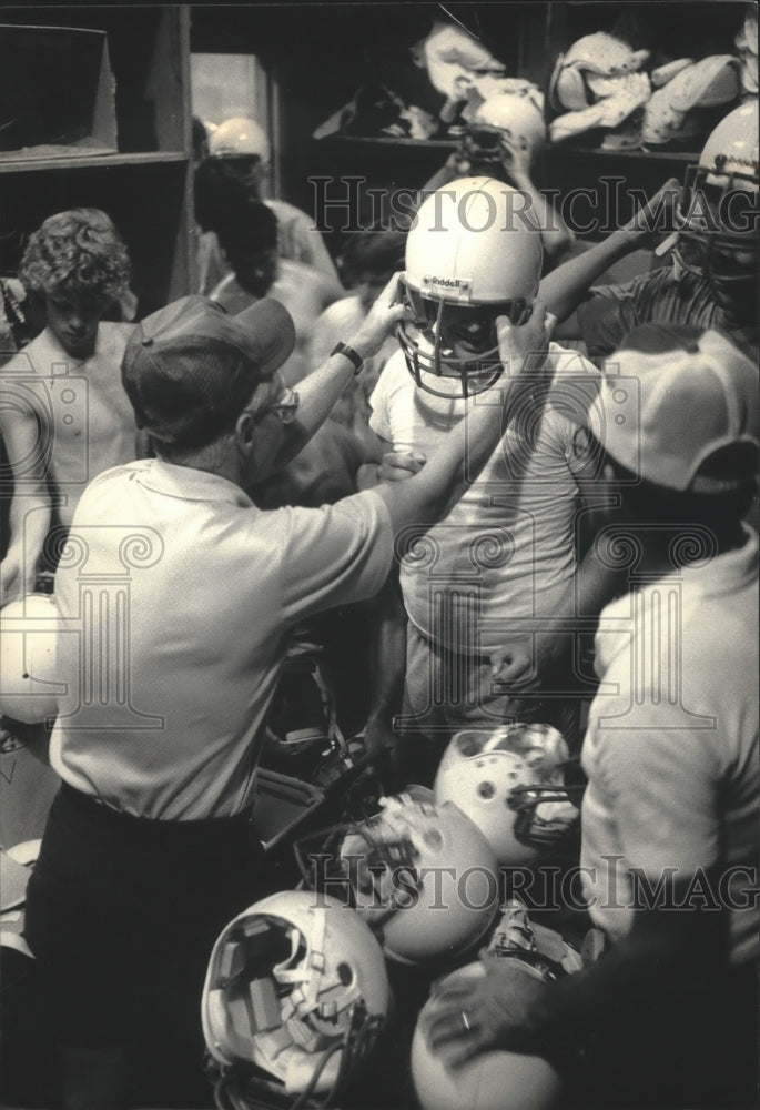 1986 Press Photo Port Washington football coaches fit players with helmet - Historic Images