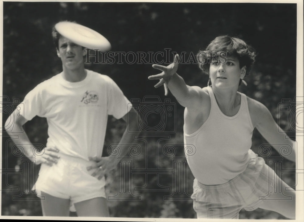 1986 Press Photo Bethany Porter playing disc golf as John Elsner watches. - Historic Images