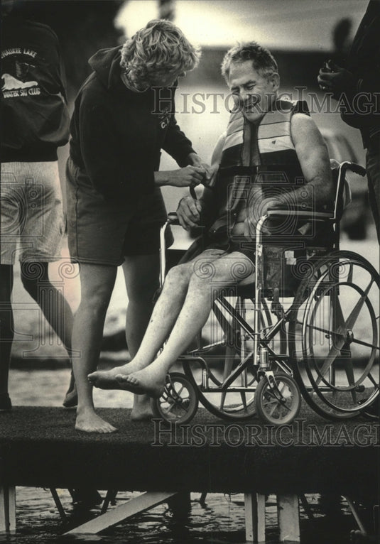 1989 Betty Brisk helps Tom Schultz with water ski flotation vest - Historic Images