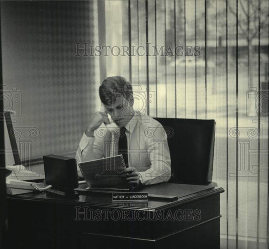 1985 Ex-football player Matt Vanden Boom at desk in business career. - Historic Images