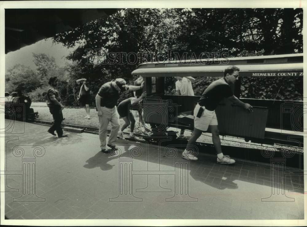 1990 Press Photo Zoo workers push crippled train car after it was hit by a train - Historic Images